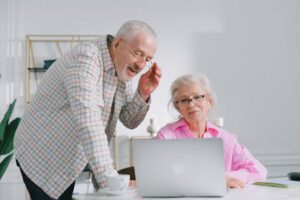 Senior couple enjoying a conversation while using a laptop indoors, showcasing active lifestyle.